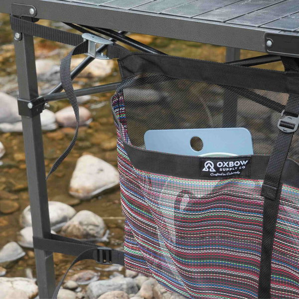 Camp table storage bag attached to folding table with cam straps
